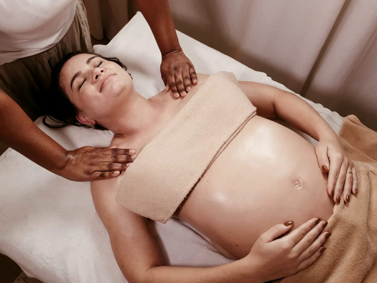 Eine schwangere Frau erhält in Seitenlage eine sanfte Massage.